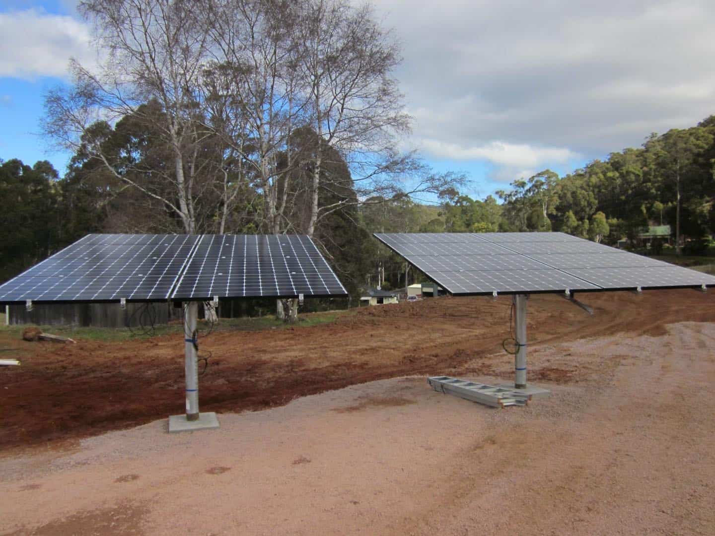 Pole mounted solar array in a paddock beside a rural driveway