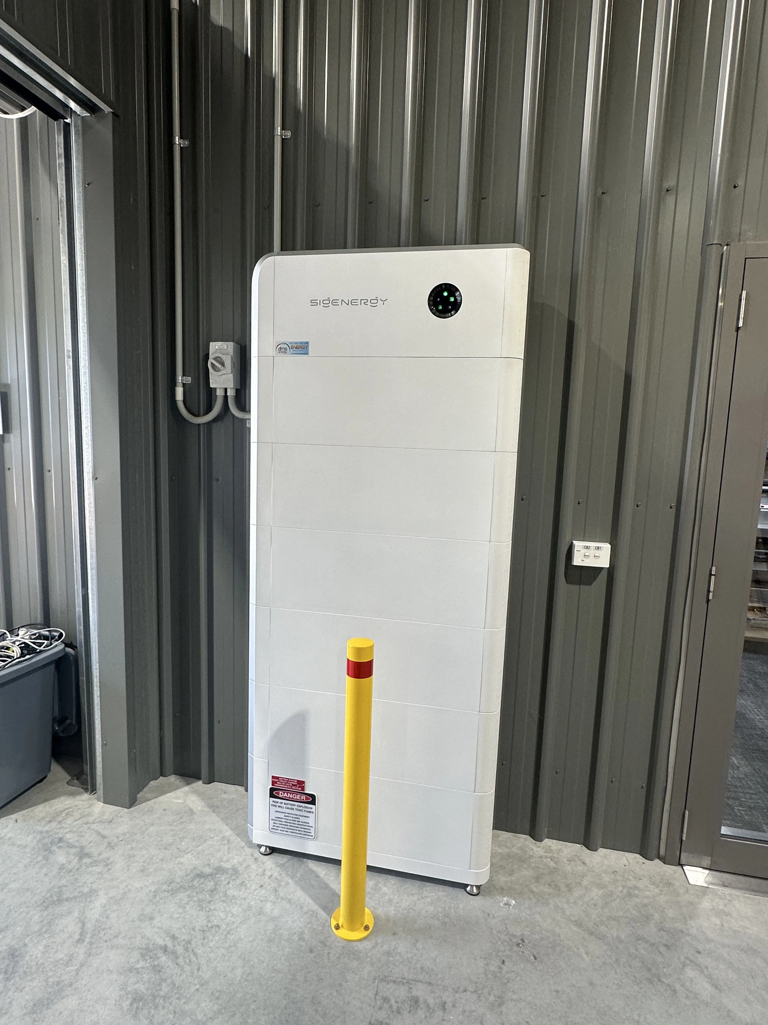 A Sigenergy battery installed against a colorbond wall by DMS Energy