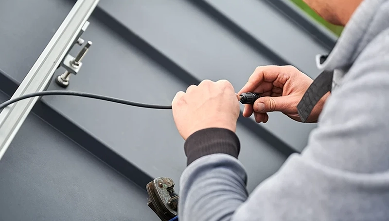 An electrician repairing solar panel cabling on a roof